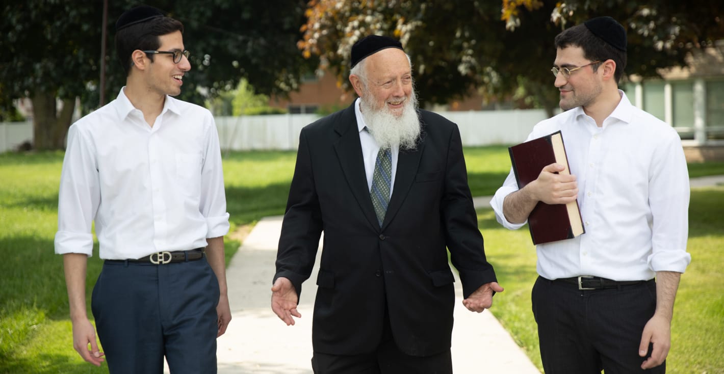 two male students and faculty member walking outside