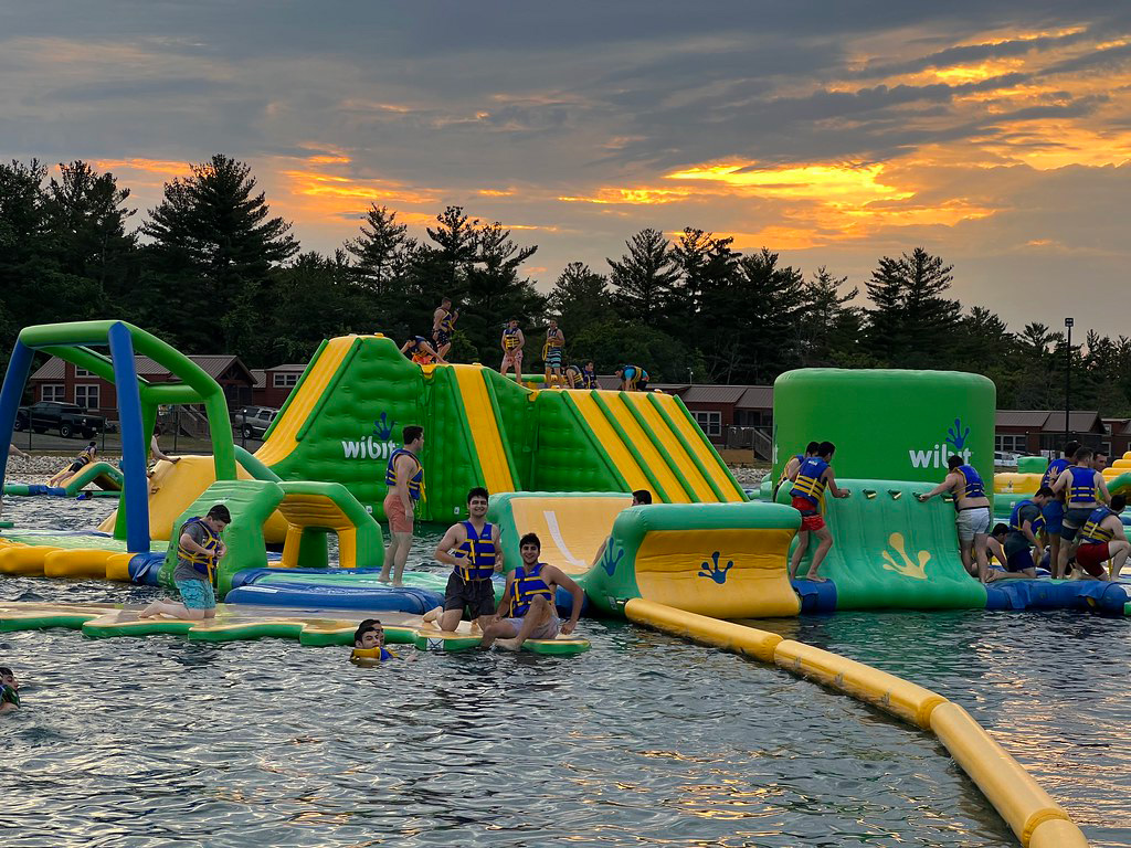 Campers playing on bounce house that floats on the water