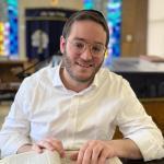 Rabbi Yair Olstein sitting at table with religious text